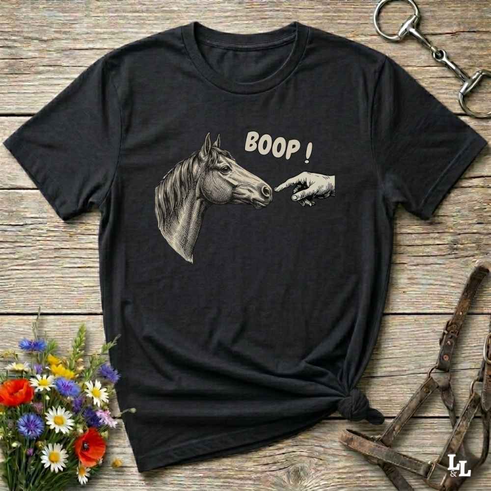 Black t-shirt with horse and hand graphic and 'BOOP!' text on a wooden surface with floral and equestrian elements.