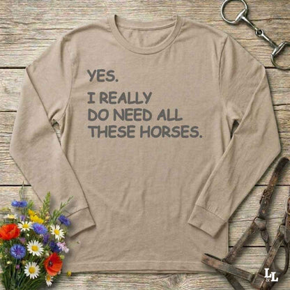 Beige long-sleeve shirt with text on a wooden surface with floral and equestrian equipment.