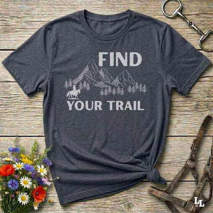 Gray t-shirt with 'Find Your Trail' graphic on a wooden surface with flowers and horse equipment.