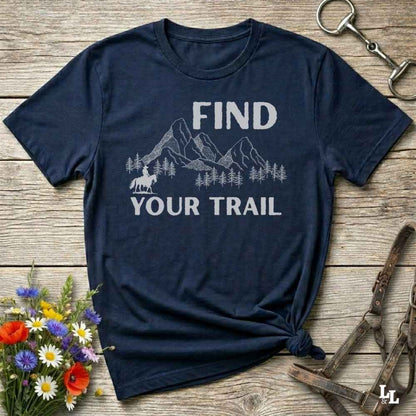 Navy blue t-shirt with 'Find Your Trail' graphic on a wooden surface with flowers and horse equipment.