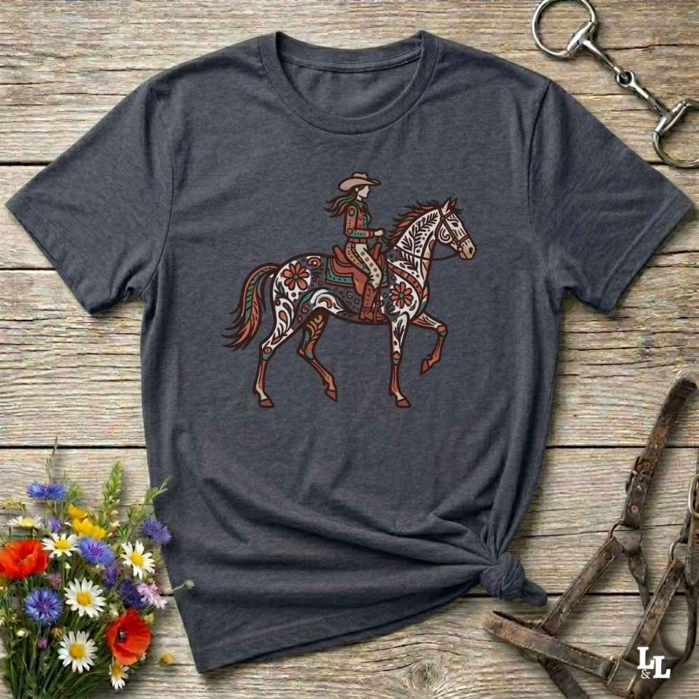 Gray t-shirt with a graphic of a woman riding a horse on a wooden surface with floral and equestrian accessories.