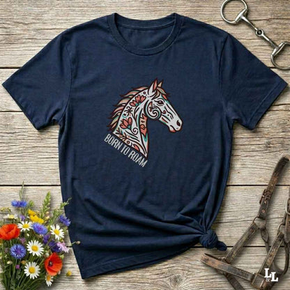 Navy blue t-shirt with a colorful horse graphic and 'Born to Roam' text on a wooden surface with floral and equestrian-themed accessories.