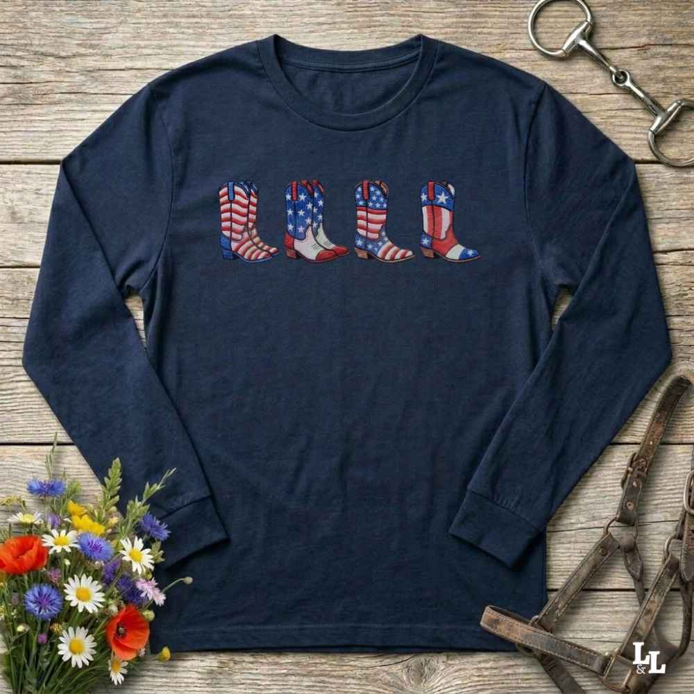 Navy long-sleeve shirt with American flag cowboy boots design on a wooden surface with floral and equestrian elements.