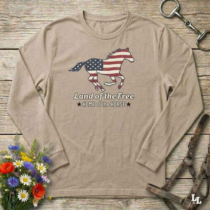 Beige long-sleeve shirt with American flag horse design on a wooden surface with floral and equestrian elements.