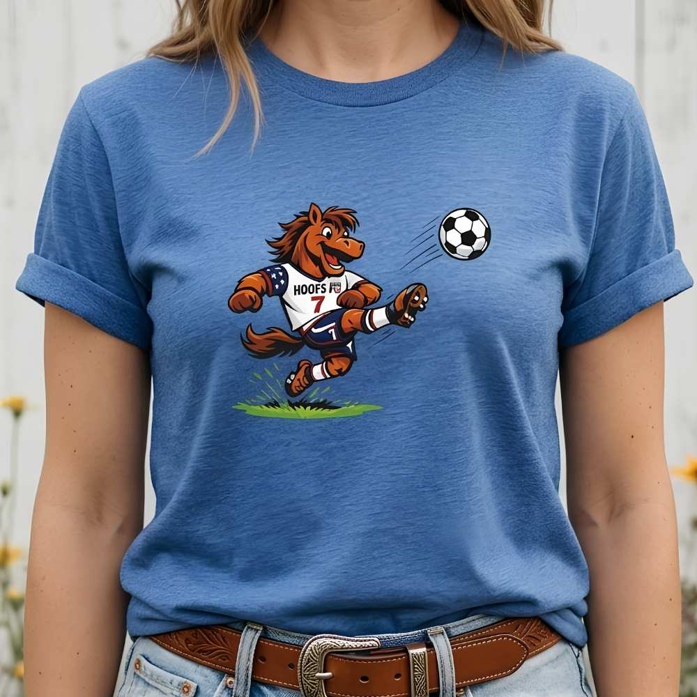 person wearing blue t-shirt with a cartoon horse kicking a soccer ball on a wooden surface with flowers and horse halter and bit.