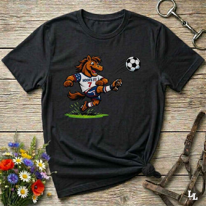 black t-shirt with a cartoon horse kicking a soccer ball on a wooden surface with flowers and horse halter and bit.