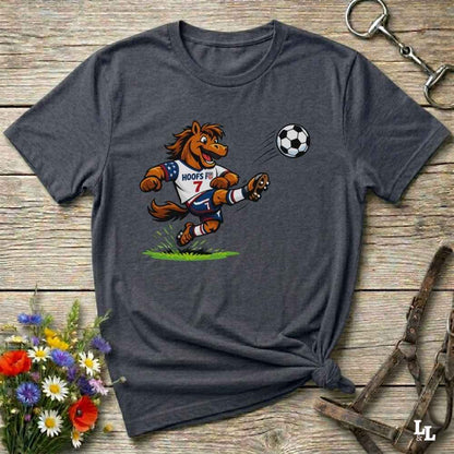gray t-shirt with a cartoon horse kicking a soccer ball on a wooden surface with flowers and horse halter and bit.