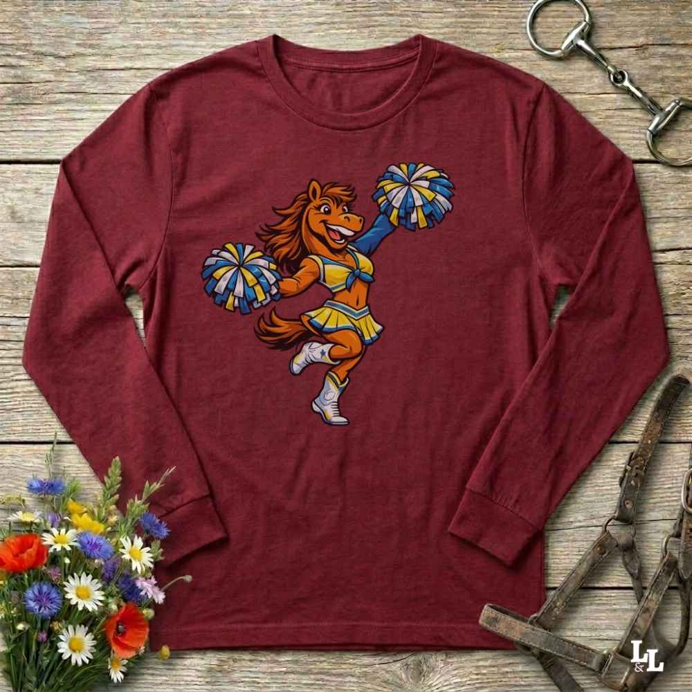 Maroon long-sleeve shirt with a cartoon lion in a cheerleader outfit on a wooden surface with flowers and a bottle opener.