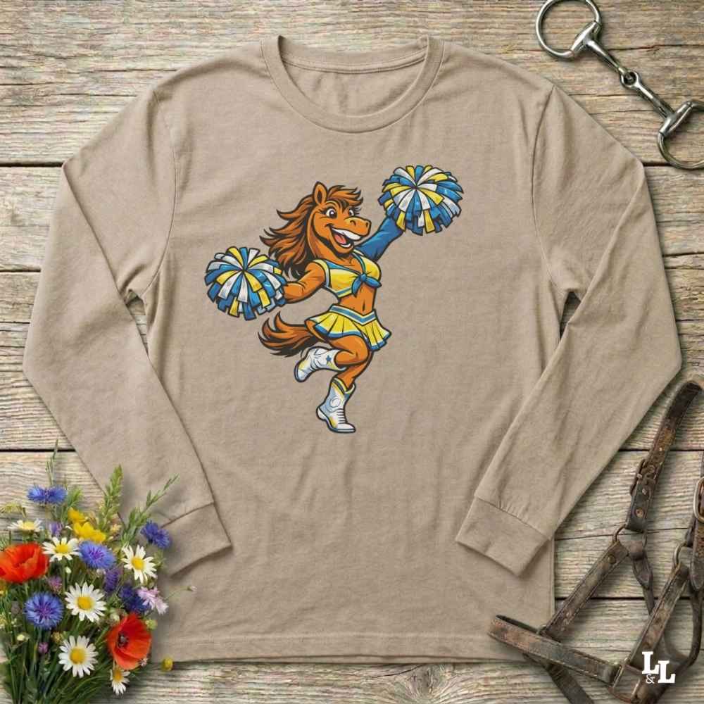 Beige long-sleeve shirt with a cartoon horse cheerleader design on a wooden surface with flowers and horse equipment.