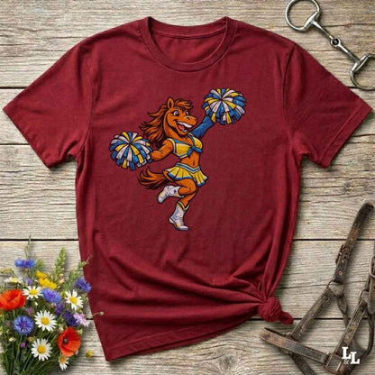 red  t-shirt with a cartoon horse cheerleader design on a wooden surface with flowers and a horse bit