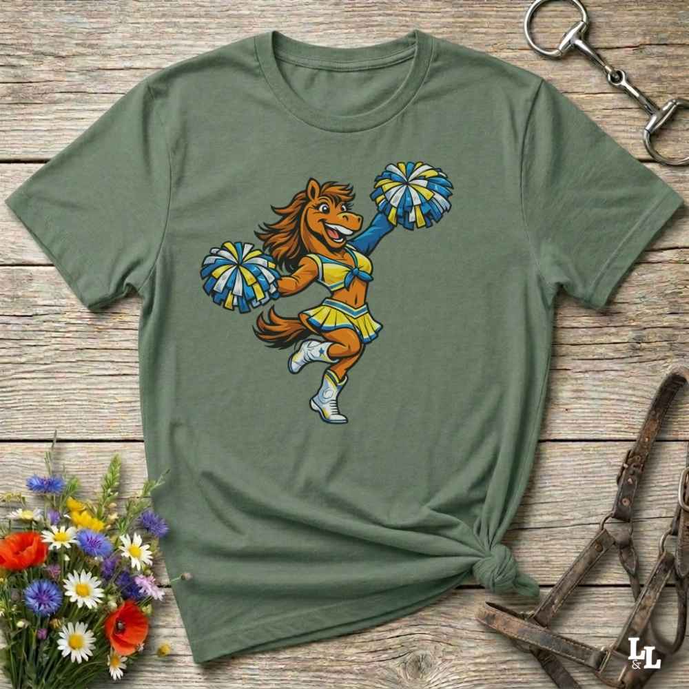 green  t-shirt with a cartoon horse cheerleader design on a wooden surface with flowers and a horse bit