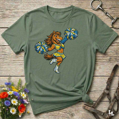 green  t-shirt with a cartoon horse cheerleader design on a wooden surface with flowers and a horse bit