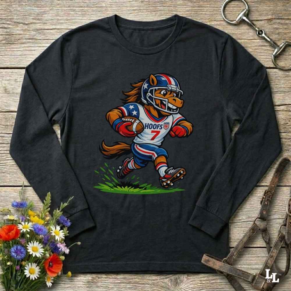 A black long-sleeve t-shirt with a cartoon graphic of a horse running as an American football player, styled on a rustic wooden background with flowers and horse tack.