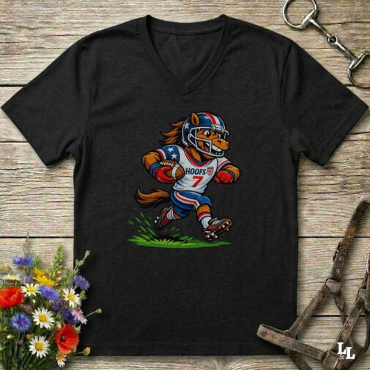A black V-neck t-shirt laid flat on a rustic wooden surface, featuring a cartoon graphic of a horse mascot in a football uniform with the number 7. The shirt is styled with equestrian tack in the background and a small bouquet of flowers in the lower-left corner.