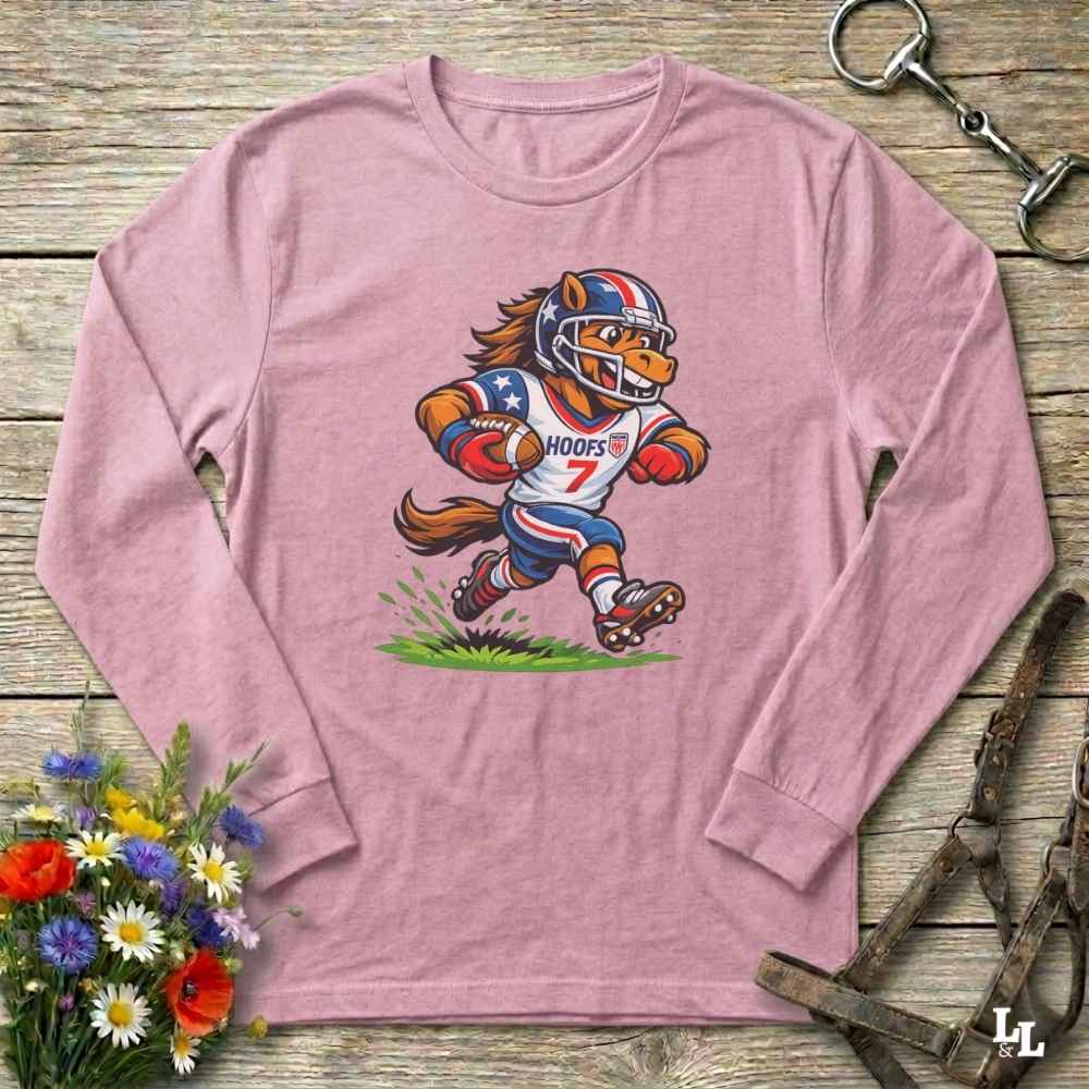 Pink long-sleeve shirt with a cartoon football player design on a wooden surface with flowers and a belt.