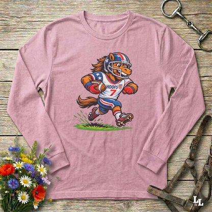 Pink long-sleeve shirt with a cartoon football player design on a wooden surface with flowers and a belt.