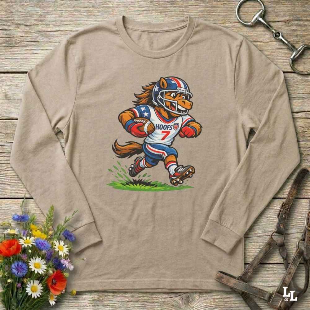 Beige long-sleeve shirt with a cartoon horse in a american football uniform on a wooden surface with flowers and a horse halter and bit.