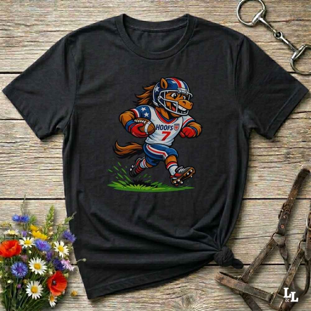 Black t-shirt with a cartoon football player design on a wooden surface with flowers and a keychain.