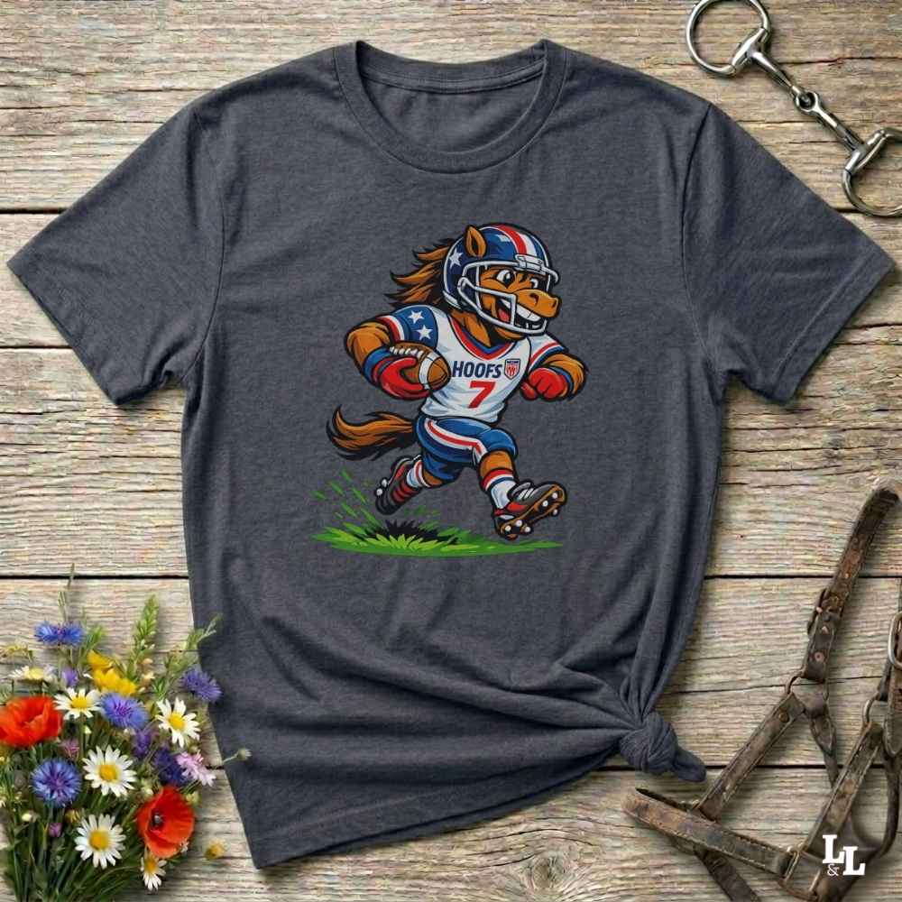 Gray t-shirt with a cartoon football player design on a wooden surface with flowers and a keychain.