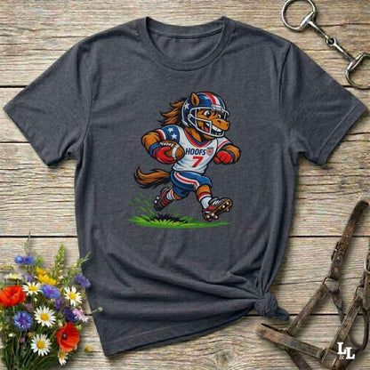 Gray t-shirt with a cartoon football player design on a wooden surface with flowers and a keychain.