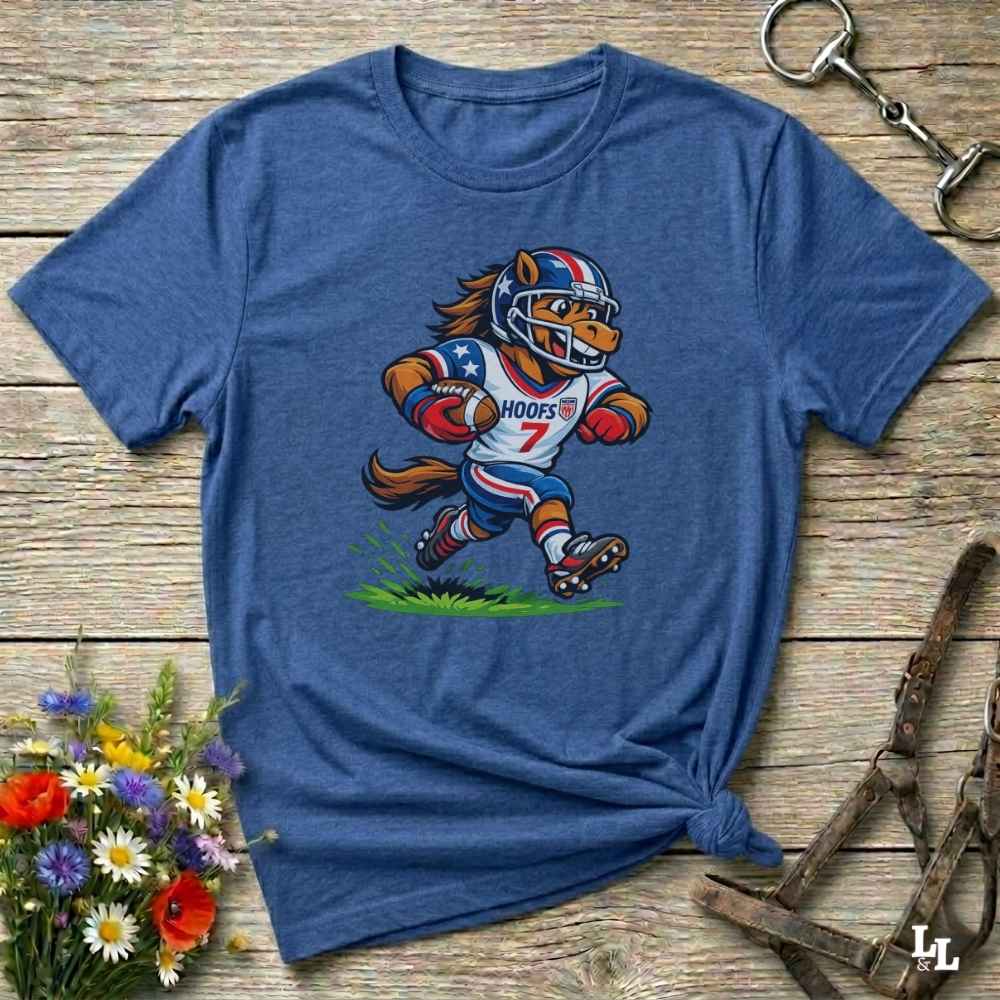 Blue t-shirt with a cartoon football player design on a wooden surface with flowers and a keychain.