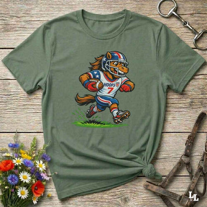 Green t-shirt with a cartoon football player design on a wooden surface with flowers and a bottle opener.