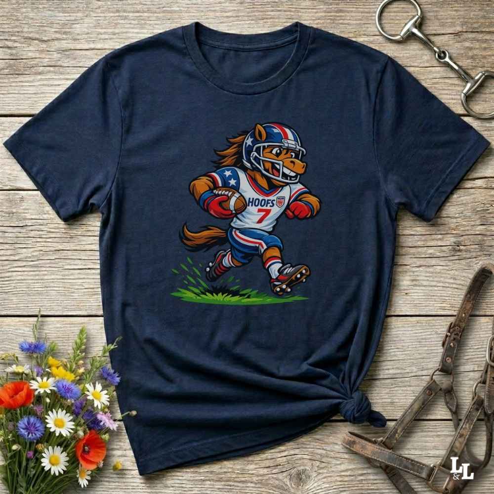 Navy blue t-shirt with a cartoon football player design on a wooden surface with flowers and tools.