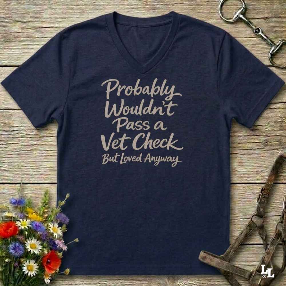 navy v-neck t-shirt, with text "Probably Wouldn't Pass a Vet Check, bu tloved anyway". T-shirt lying on barn wooden floorboards, with flowers, horse halter and horse bit.