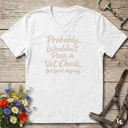 white v-neck t-shirt, with text "Probably Wouldn't Pass a Vet Check, bu tloved anyway". T-shirt lying on barn wooden floorboards, with flowers, horse halter and horse bit.