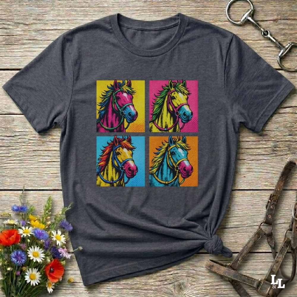 A dark gray heather t-shirt with a colorful pop-art graphic of four horses in a four-square grid, styled on a rustic wooden background with a horse halter and flowers.