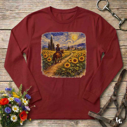 A long-sleeve crewneck t-shirt in maroon red, featuring a square graphic print of a cowboy riding through a sunflower field in a Van Gogh-inspired style. The shirt is displayed flat on a rustic wooden background with equestrian and floral props.