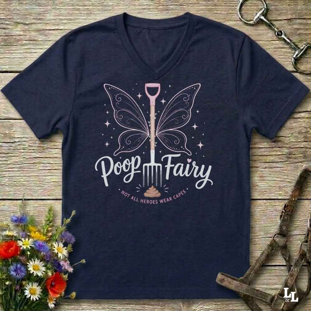 A navy blue V-neck t-shirt with a graphic of a fairy-shovel and the text 'Poop Fairy - NOT ALL HEROES WEAR CAESARS' on a rustic wooden background with equestrian accessories and flowers.