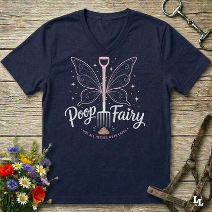 A navy blue V-neck t-shirt with a graphic of a fairy-shovel and the text 'Poop Fairy - NOT ALL HEROES WEAR CAESARS' on a rustic wooden background with equestrian accessories and flowers.