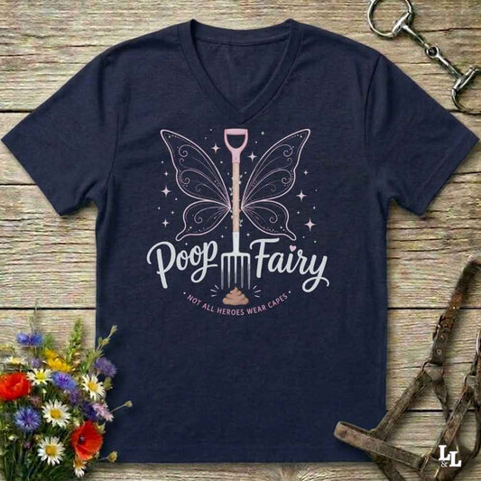 A navy blue V-neck t-shirt with a graphic of a fairy-shovel and the text 'Poop Fairy - NOT ALL HEROES WEAR CAESARS' on a rustic wooden background with equestrian accessories and flowers.