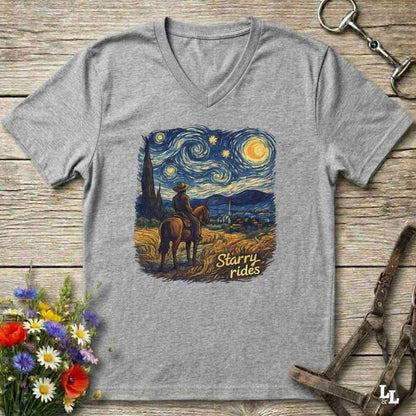A heather gray V-neck t-shirt laid flat on a rustic wooden surface, featuring a colorful graphic print of a cowboy riding a horse under a swirling 'Starry Night' sky. The text 'Starry rides' is printed in yellow in the lower right of the graphic.