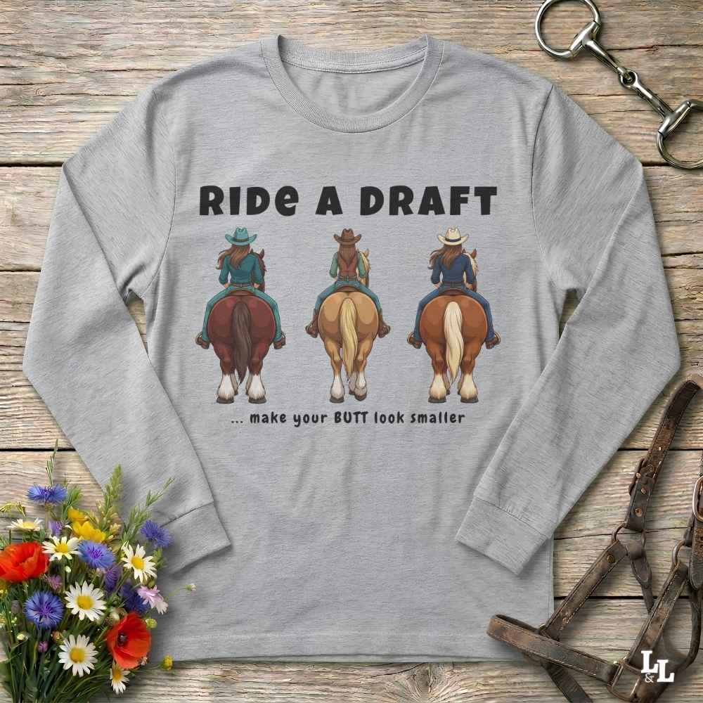 A light gray long-sleeve t-shirt with a graphic print of three cowboys riding horses and the text 'RIDE A DRAFT .
