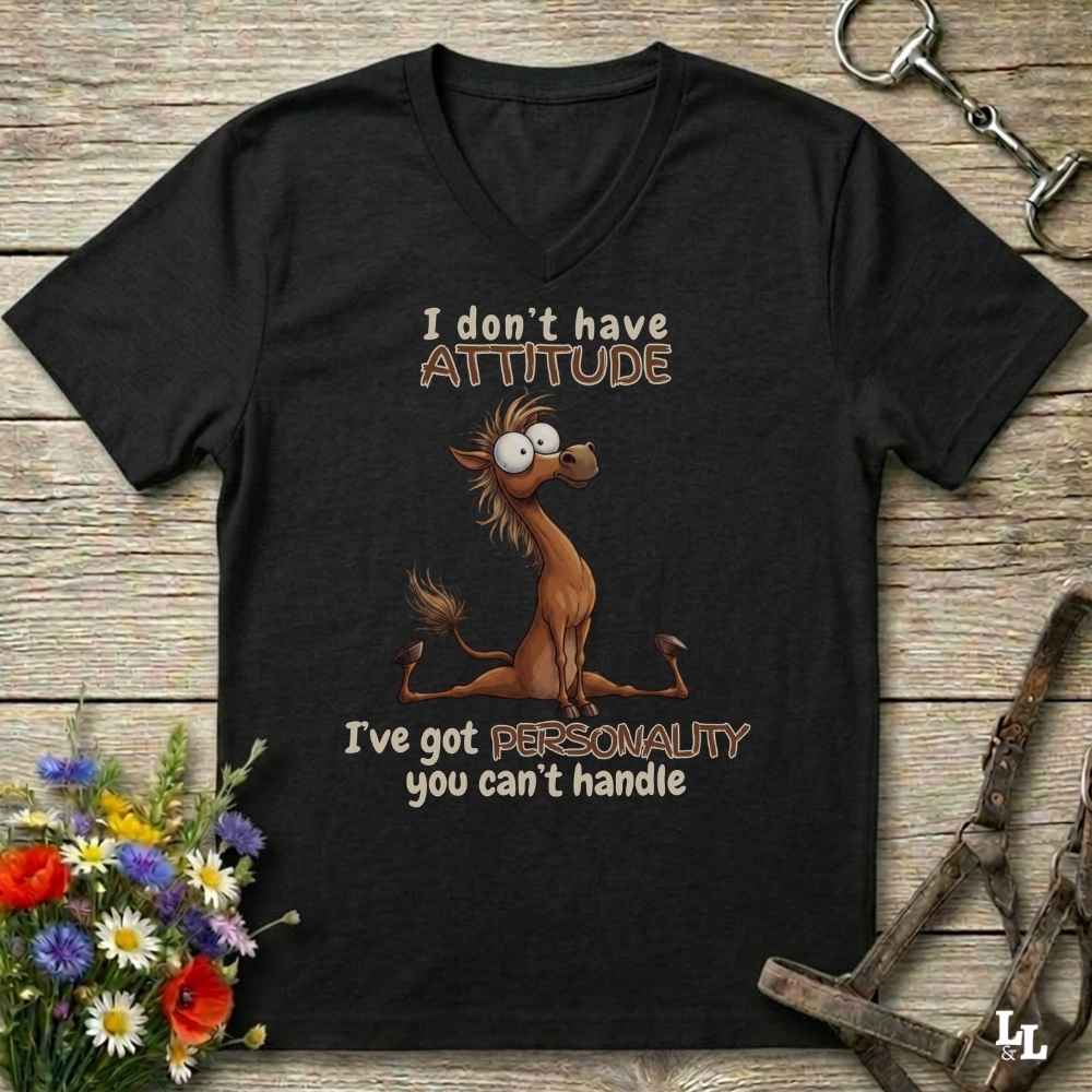 A black V-neck t-shirt with a humorous horse graphic and text, displayed on a rustic wooden background with decorative flowers and horse tack.