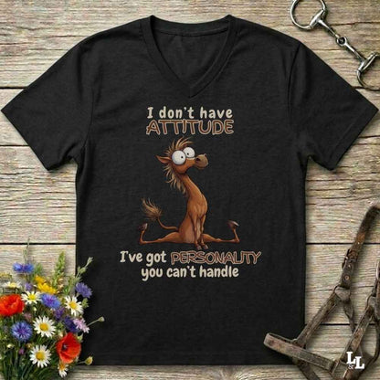 A black V-neck t-shirt with a humorous horse graphic and text, displayed on a rustic wooden background with decorative flowers and horse tack.