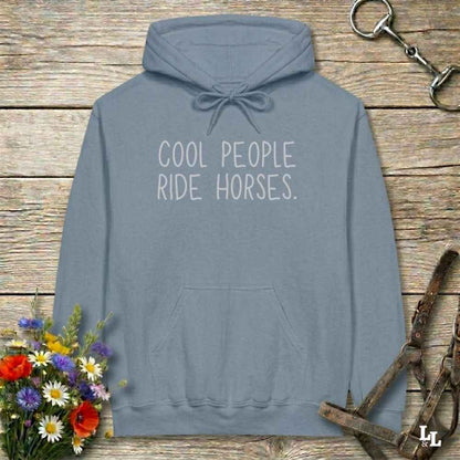 Gray hoodie with 'tremendous horse girl energy believe me' text on a wooden surface with floral and equestrian accessories.