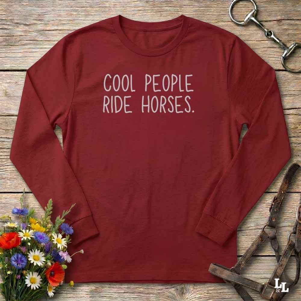 A long-sleeve crewneck shirt in burgundy red with the text 'COOL PEOPLE RIDE HORSES.' printed in white across the chest.