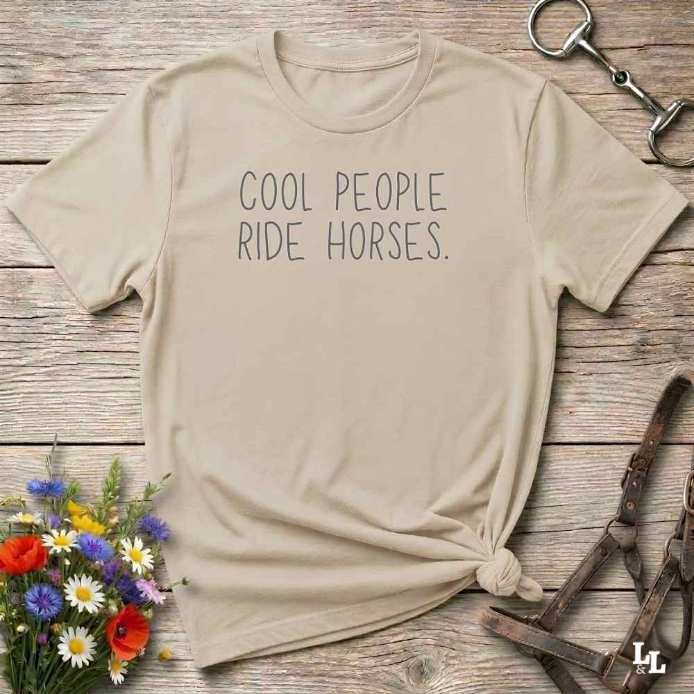 A beige graphic t-shirt with the text 'COOL PEOPLE RIDE HORSES.' printed in dark gray.