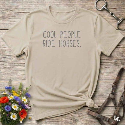 A beige graphic t-shirt with the text 'COOL PEOPLE RIDE HORSES.' printed in dark gray.
