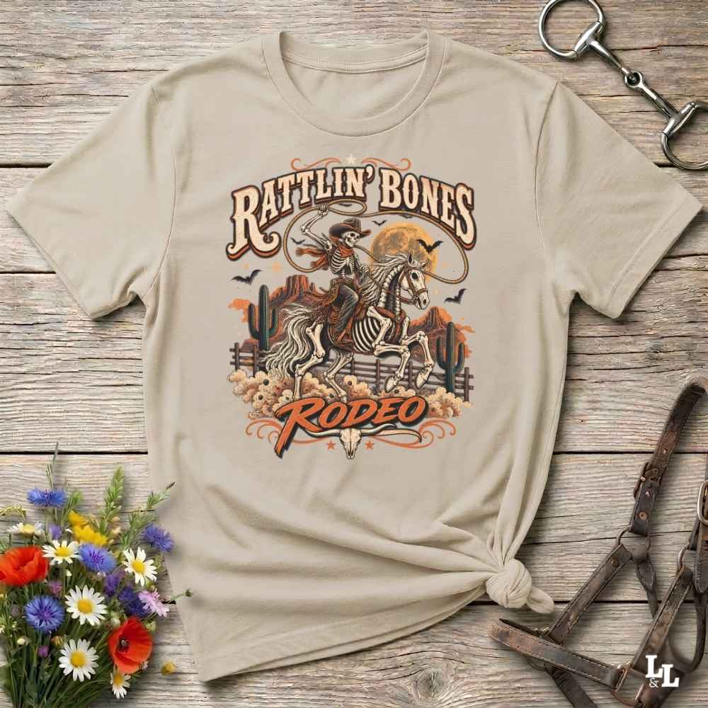 beige t-shirt with short sleeves, with halloween design of rattlin'bones rodeo, with skull cowboy riding a horse in the desert