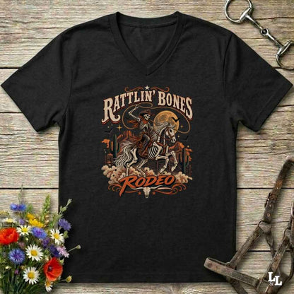 A black  Halloween V-neck t-shirt with a detailed western skeleton cowboy graphic on the chest, styled in a flat-lay on a rustic wooden background with equestrian and floral props.