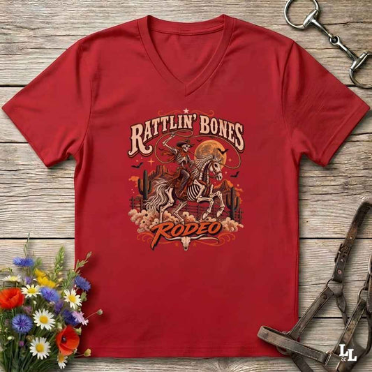 A red  Halloween V-neck t-shirt with a detailed western skeleton cowboy graphic on the chest, styled in a flat-lay on a rustic wooden background with equestrian and floral props.