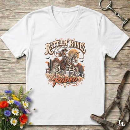 A white Halloween V-neck t-shirt with a detailed western skeleton cowboy graphic on the chest, styled in a flat-lay on a rustic wooden background with equestrian and floral props.