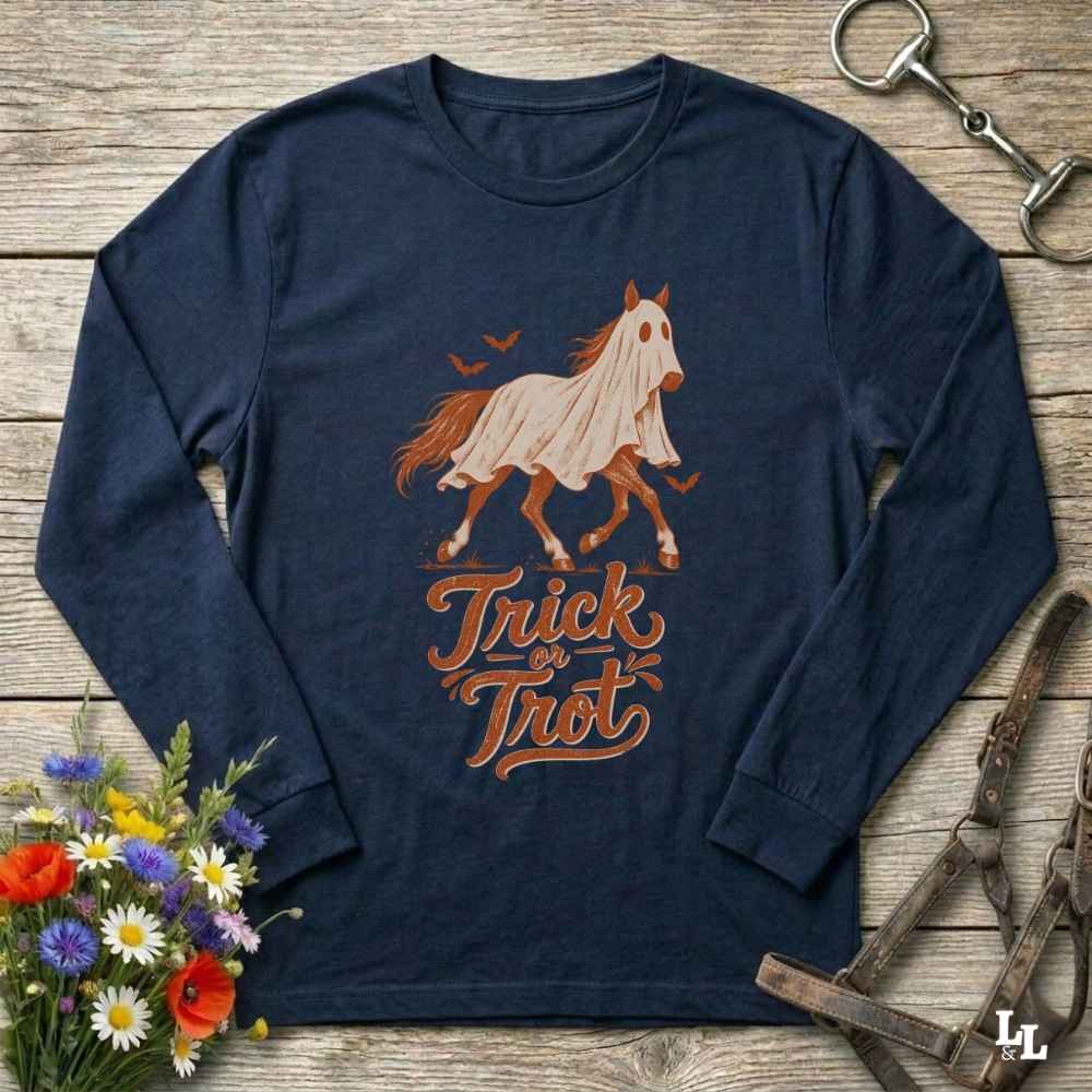 A navy blue long-sleeve t-shirt with a 'Trick or Treat' horse graphic, laid flat on a rustic wooden background with equestrian and floral props.