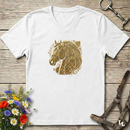 A white V-neck t-shirt featuring a detailed gold horse head graphic on the chest, styled in a flat-lay on a rustic wooden background with equestrian accessories and flowers.
