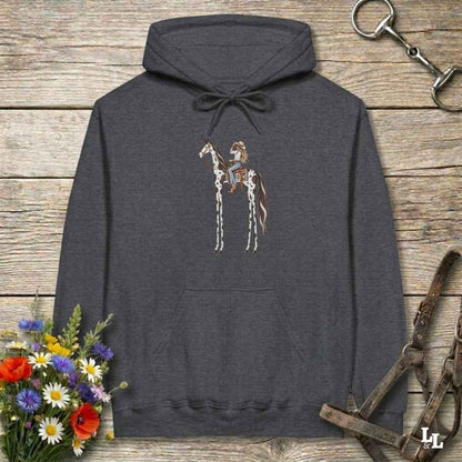 A dark heather gray hoodie laid flat on a rustic wooden surface, featuring a graphic of a tall horse with rider.. The hoodie is styled with equestrian-themed props including a halter, tack, and a small bouquet of wildflowers.