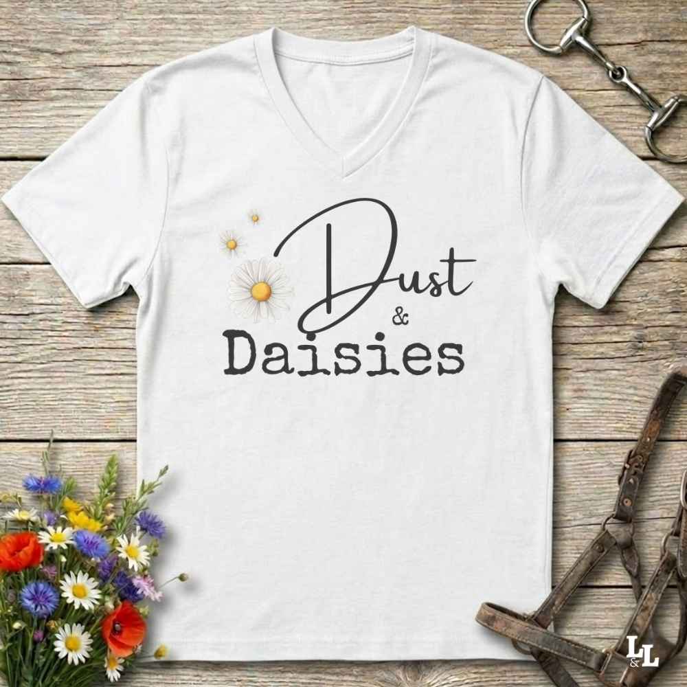 A white V-neck t-shirt with 'Dust & Daisies' printed on the front, styled in a flat-lay on a rustic wooden background with equestrian and floral props.